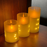 Three illuminated LED candles in glass holders on a wooden surface.