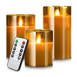 Set of three flameless candles with gold accents and a remote control on a white background